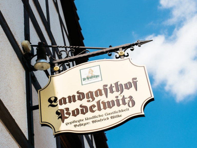 Ein Schild hängt an einer Laterne vor einer Fachwerkfassade mit der Aufschrift Landgasthof.
