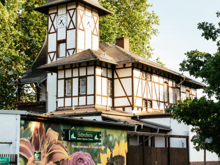 Ein Fachwerkhaus mit weißer und dunkelbrauner Struktur steht hinter einem Blumenwerbeplakat.