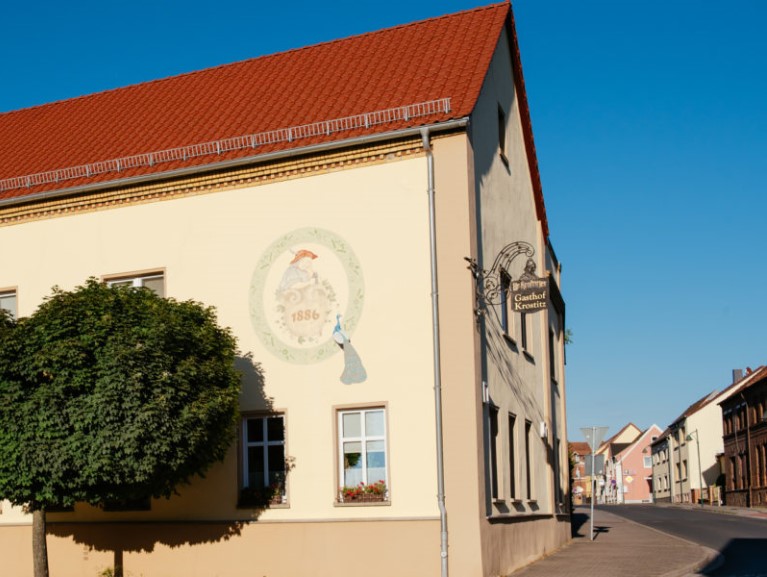 Ein großes Gebäude mit rotem Dach und Wandmalerei befindet sich an einer Straßenecke.