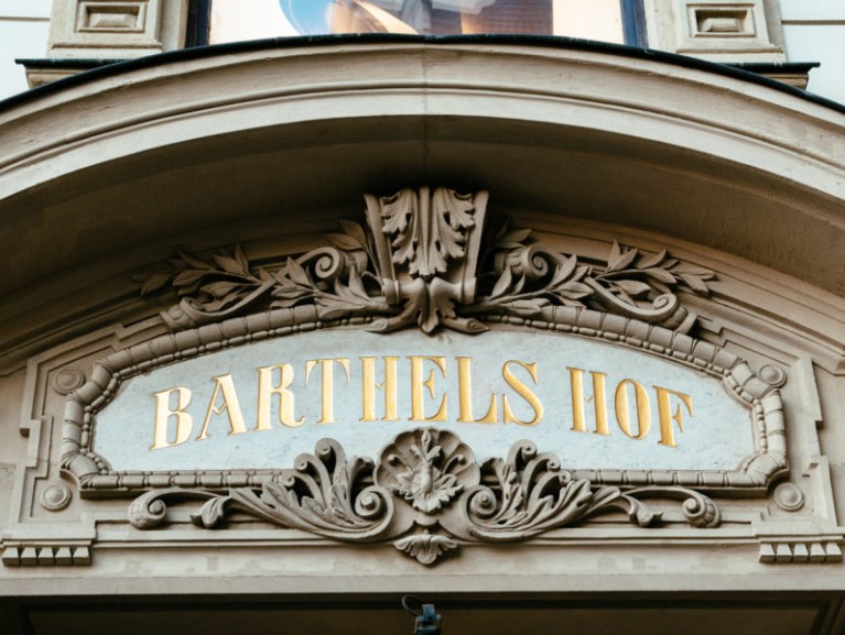 Steinbogen mit verziertem Namensschild aus Stein und goldenen Buchstaben.