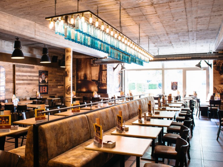 Innenansicht eines Restaurants mit Holzverkleidungen und einer länglichen blauen Flaschenlampe.