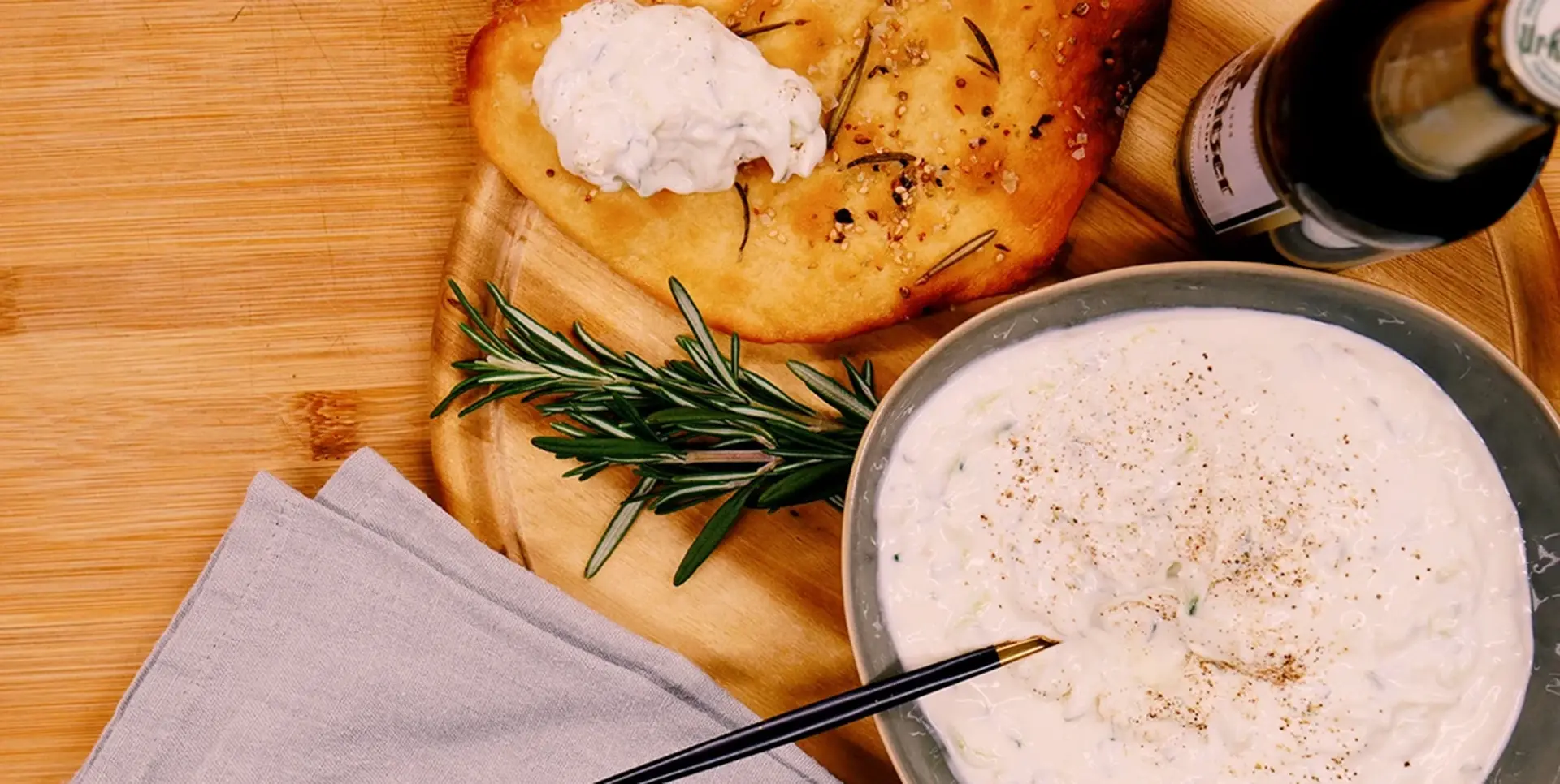 Ein frisch gebackenes Fladenbrot mit Kräutern und Topping befindet sich neben einer Schüssel Dip.